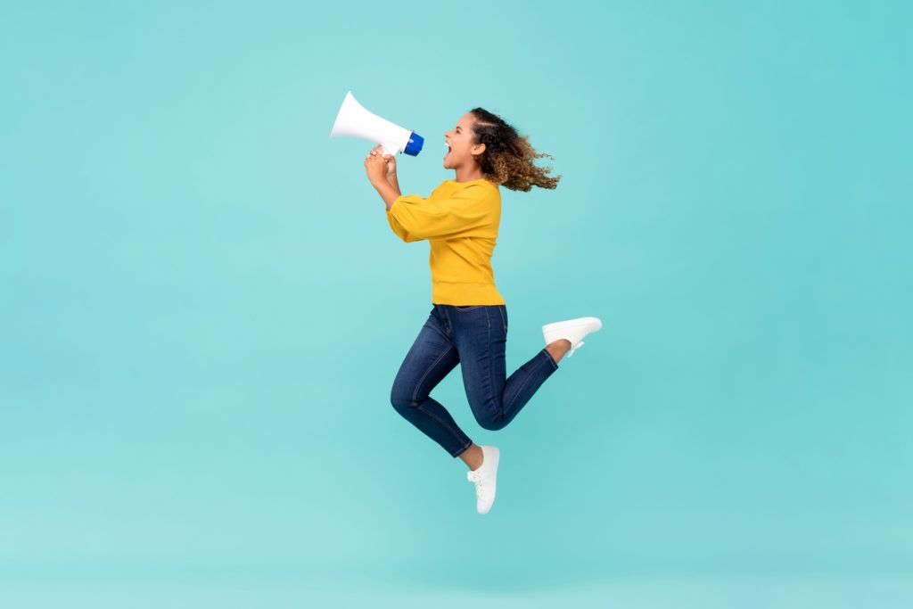 Girl with megaphone jumping and shouting