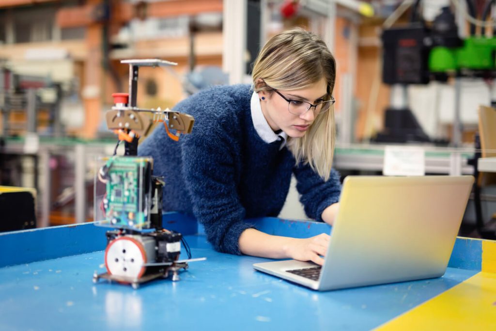 Young attractive woman engineer working on robotics project using laptop