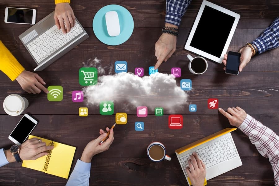 A group of people sitting around a table with devices and icons