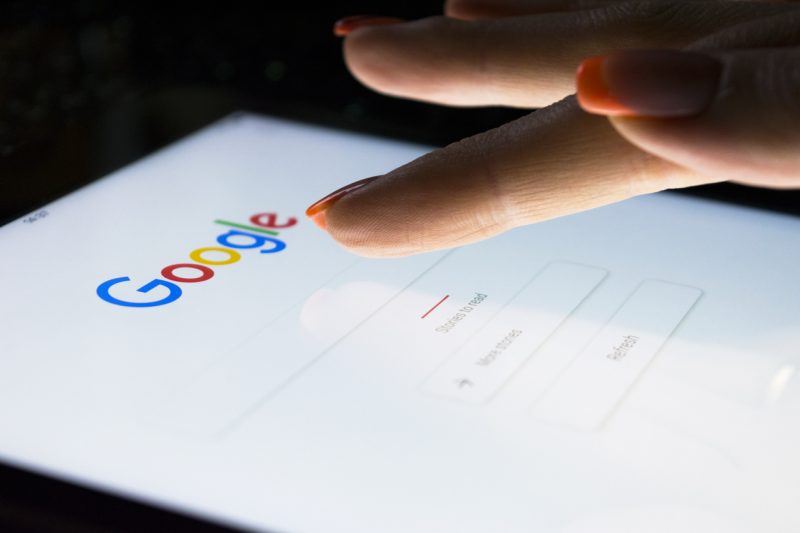 A woman's hand is touching screen on tablet computer iPad searching on Google