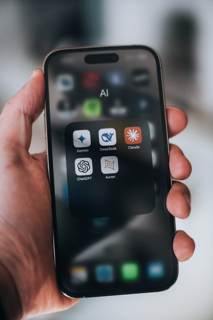 Hand holding a phone with ai application icons.